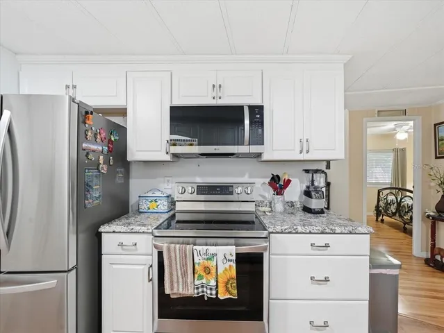 a kitchen with stainless steel appliances granite countertop a refrigerator stove and white cabinets