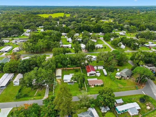 an aerial view of residential houses with outdoor space and trees