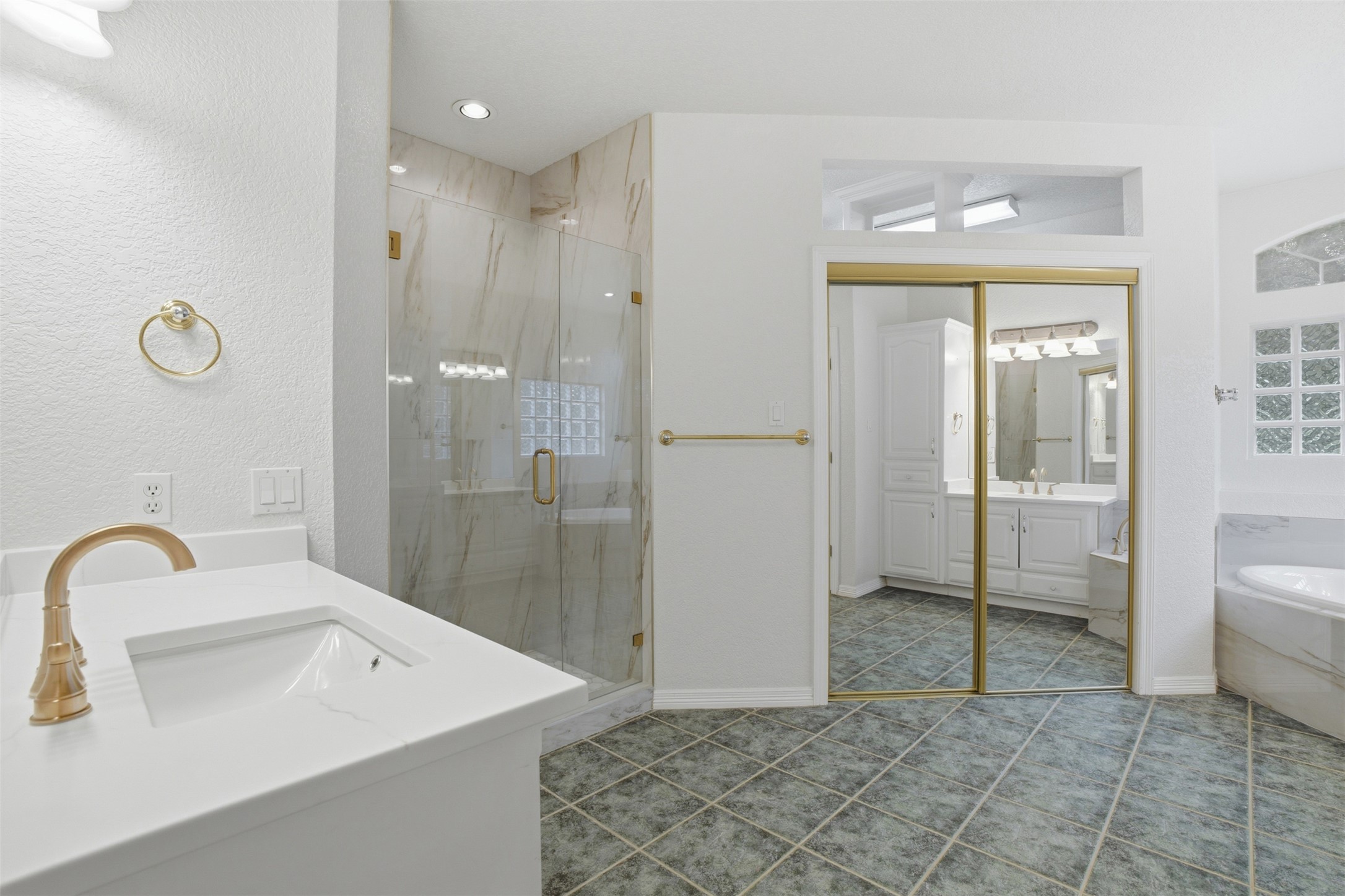 1301 County Road 262 Georgetown, TX 78633 - Photo 18 of 39 Bathroom featuring a spacious walk-in shower with glass enclosure and marble-look tile, a white vanity with integrated sink and gold-tone faucet, and large-format floor tiles