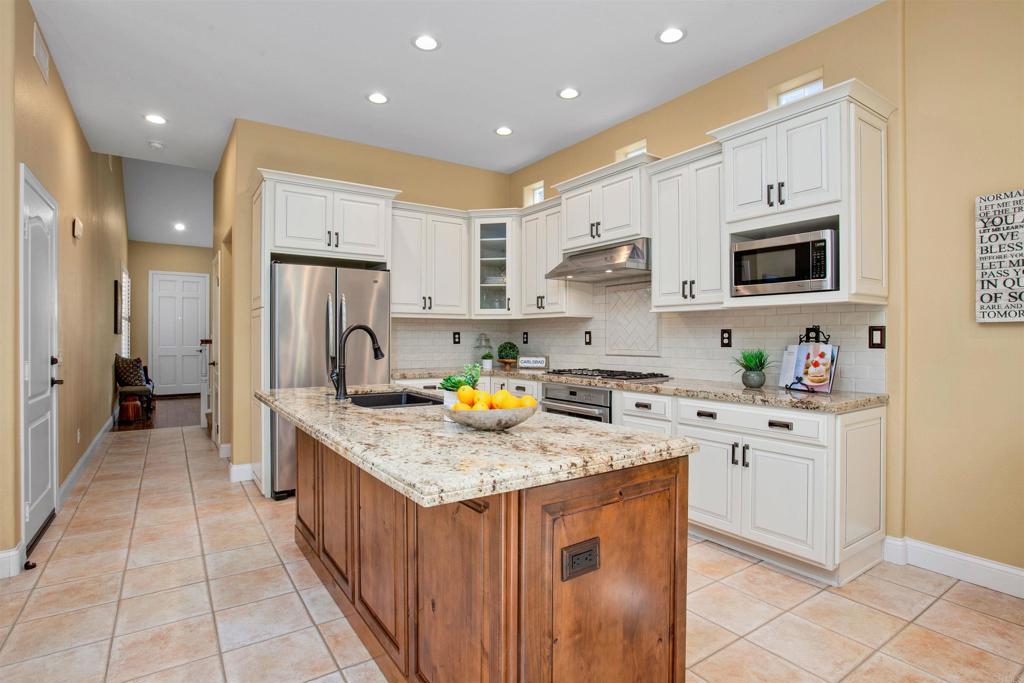 7159 Tanager Drive Carlsbad, CA 92011 - Photo 13 of 68 a kitchen with stainless steel appliances granite countertop a stove a sink and a refrigerator