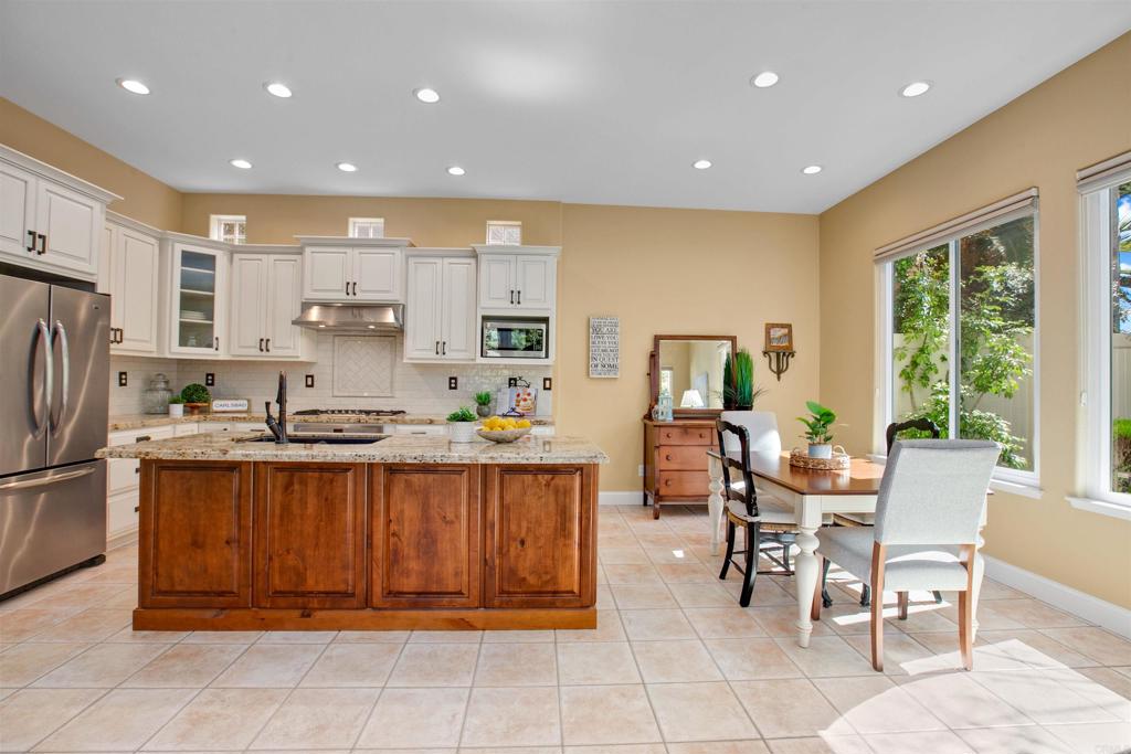 7159 Tanager Drive Carlsbad, CA 92011 - Photo 18 of 68 a kitchen with kitchen island granite countertop wooden cabinets a sink a stove and a refrigerator