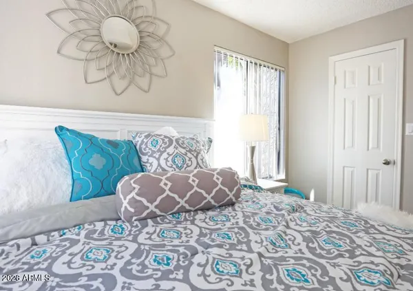 a bed sitting in a bedroom next to a window and a wooden floor