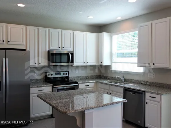 a kitchen with granite countertop white cabinets and white appliances