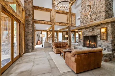a living room with furniture a fireplace and large windows