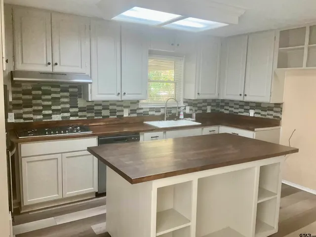 a kitchen with kitchen island granite countertop a stove a sink and white cabinets