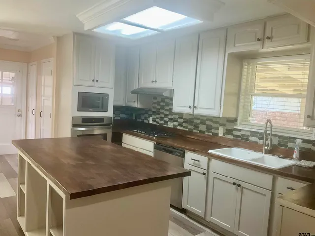 a kitchen with a sink a microwave and cabinets