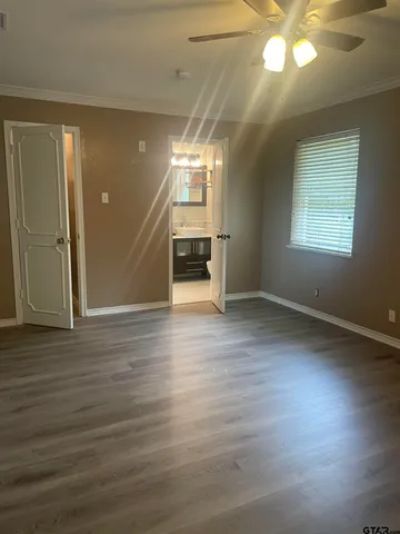 an empty room with wooden floor fan and windows