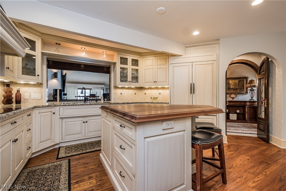 1415 Harbor Drive Northwest Canton, OH 44708 - Photo 10 of 46 Kitchen featuring island with wooden counter , white cabinetry, dark wood-type flooring, granite counters and tile backsplash