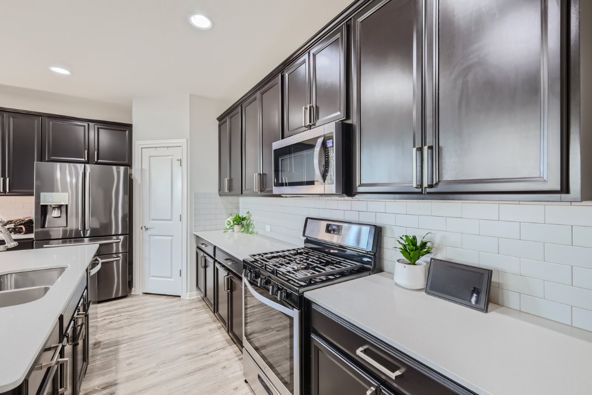 159 Bayberry Circle Buda, TX 78610 - Photo 11 of 29 a kitchen with stainless steel appliances a sink a stove and a refrigerator