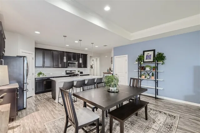 a kitchen with stainless steel appliances a stove top oven a refrigerator a sink and chairs