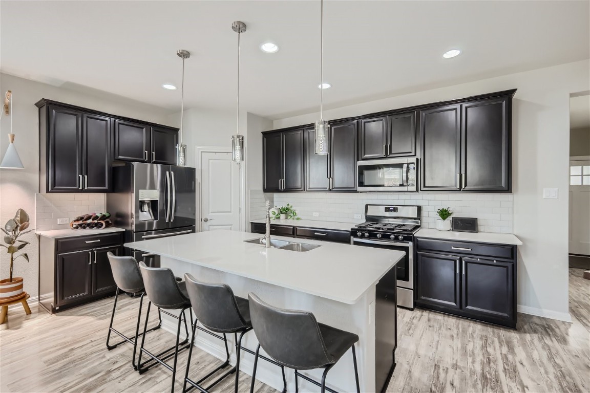 159 Bayberry Circle Buda, TX 78610 - Photo 8 of 29 a kitchen with stainless steel appliances a stove top oven a refrigerator a sink and chairs