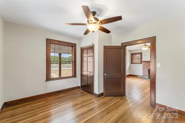 a view of empty room with wooden floor and ceiling fan