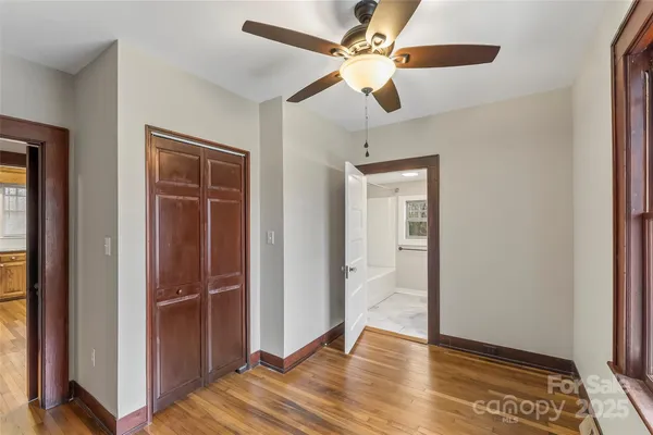 a view of a livingroom with wooden floor a ceiling fan and window