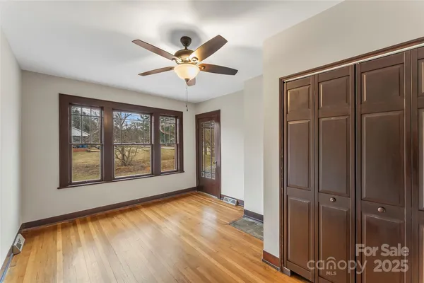 a view of an empty room with a window and wooden floor