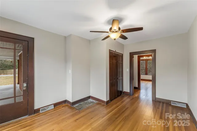 a view of empty room with wooden floor and fan
