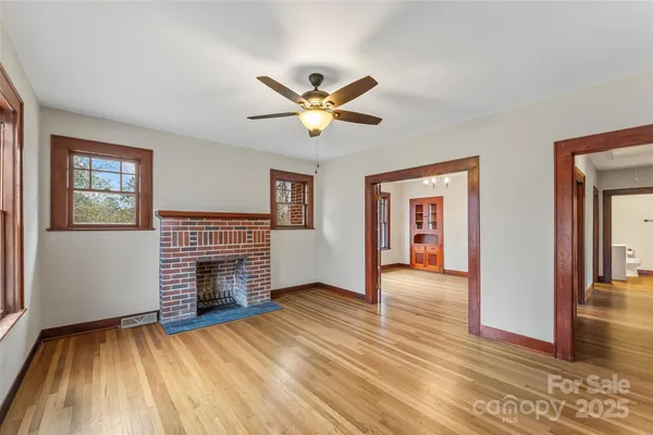 a view of an empty room with window and wooden floor