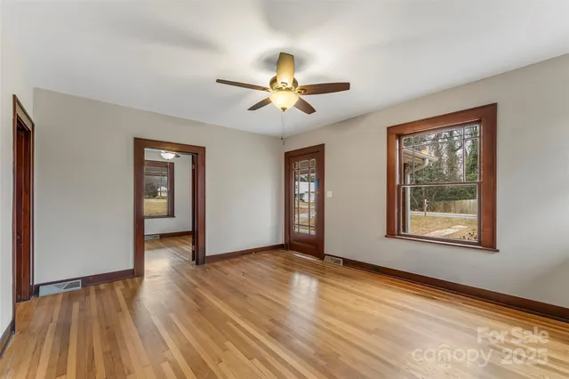 a view of an empty room with window and wooden floor