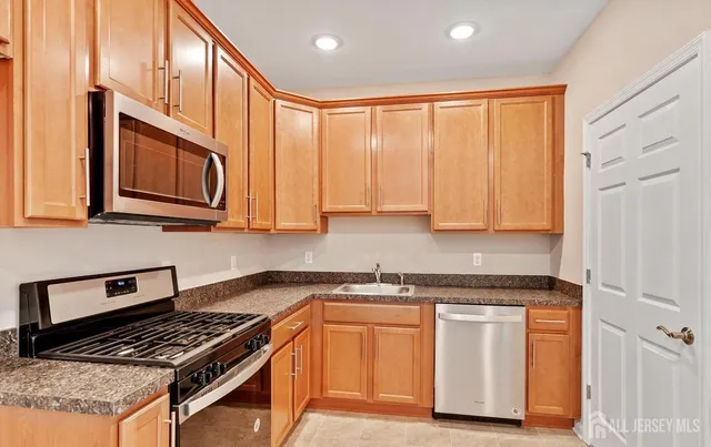 a kitchen with stainless steel appliances granite countertop a stove a sink and a microwave