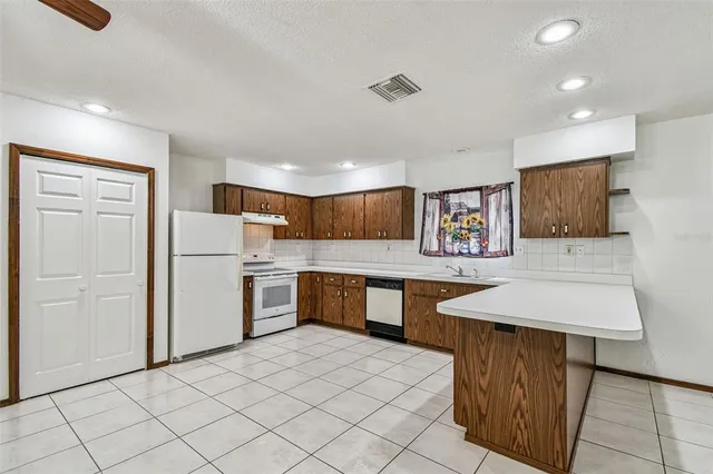 a kitchen with stainless steel appliances a stove top oven a sink dishwasher and a refrigerator with wooden floor