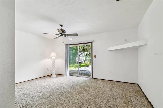 an empty room with ceiling fan and window
