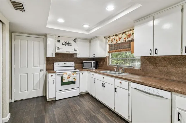 a kitchen with granite countertop white cabinets and white appliances
