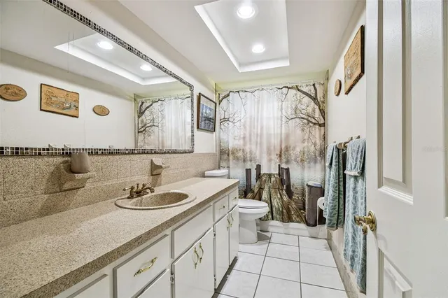 a bathroom with a granite countertop sink a toilet and shower