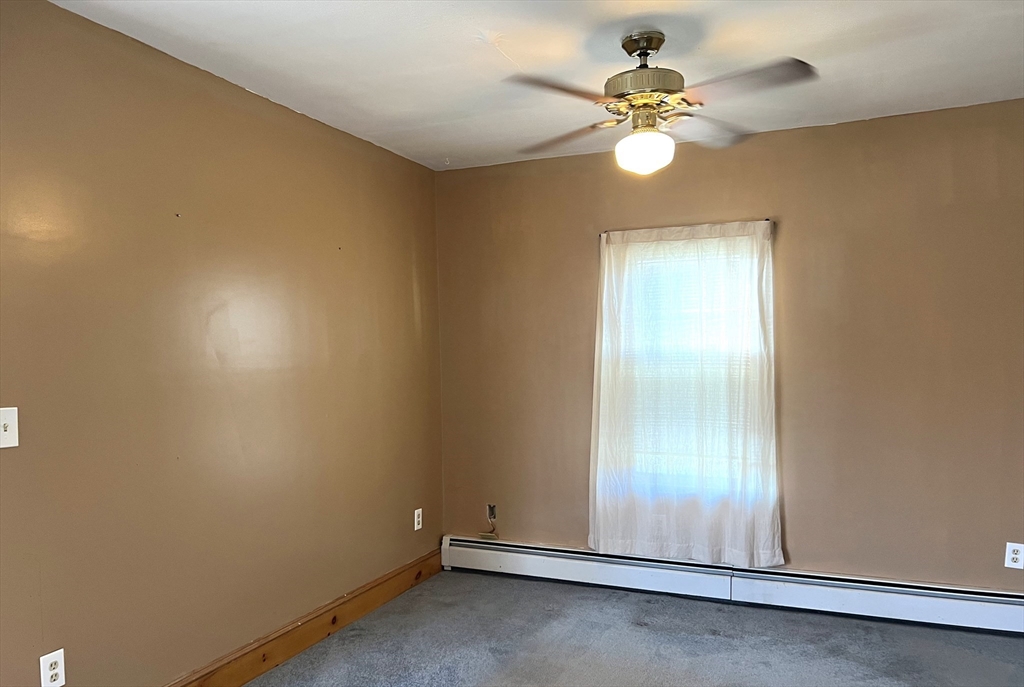 1261 G A R Highway Swansea, MA 02777 - Photo 18 of 25 an empty room with a chandelier fan and windows