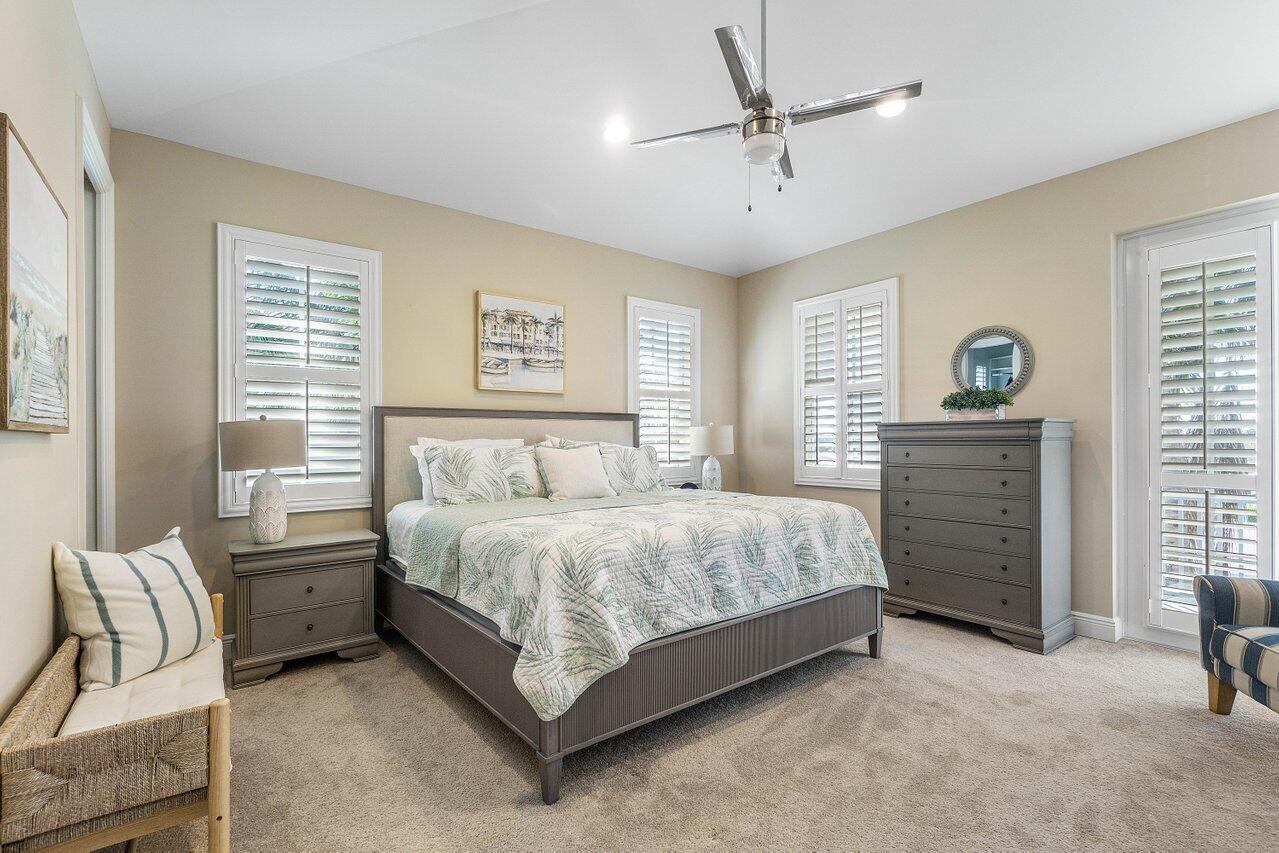 136 Ocean Breeze Drive Juno Beach, FL 33408 - Photo 13 of 30 a spacious bedroom with a bed a chandelier and a dresser