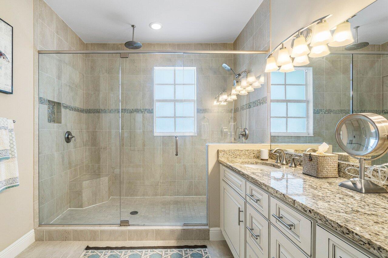 136 Ocean Breeze Drive Juno Beach, FL 33408 - Photo 16 of 30 a bathroom with a granite countertop sink a mirror and shower