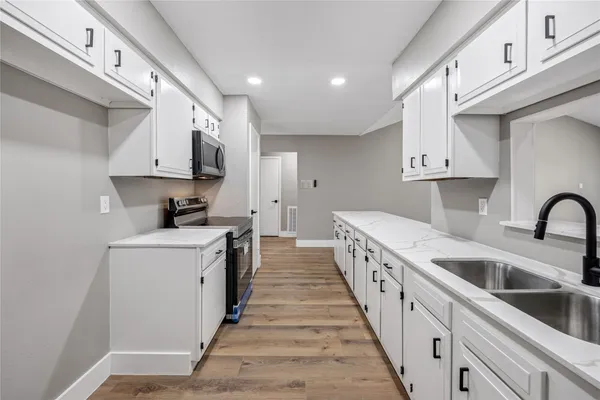 a kitchen with white cabinets appliances and sink