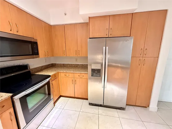 a view of kitchen and an empty room with wooden floor