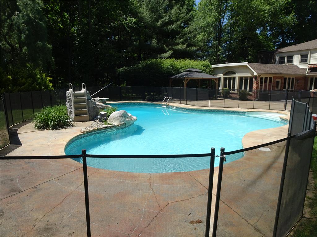 1371 Stoke Park Road Bethlehem, PA 18017 - Photo 6 of 12 An inviting backyard oasis features a fenced pool with a slide, nestled among mature trees.