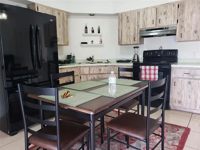 a kitchen with stainless steel appliances a dining table chairs and a refrigerator