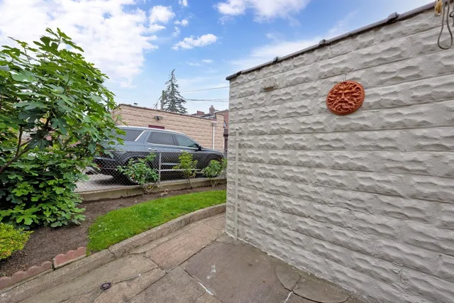 a view of a brick wall with plants and large trees