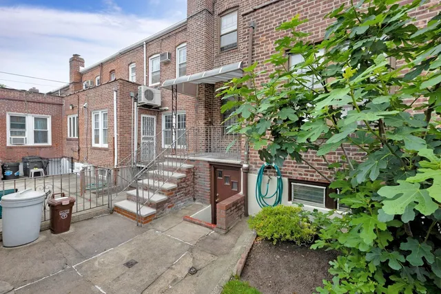 a view of a brick house with many windows plants and large tree