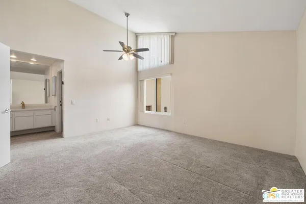 a view of a big room with a chandelier fan and windows