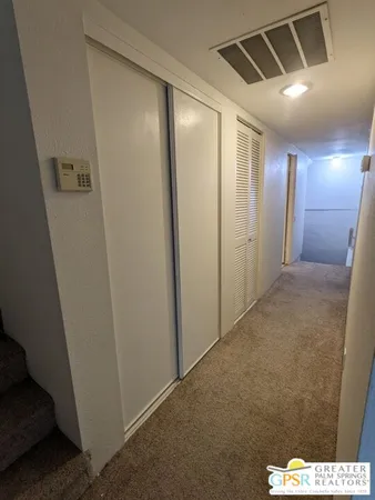 an empty room with a chandelier fan and windows