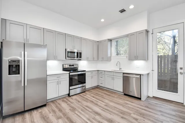 a kitchen with stainless steel appliances granite countertop a sink a stove a microwave a refrigerator a sink and white cabinets