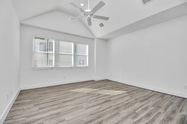 an empty room with wooden floor and a ceiling fan