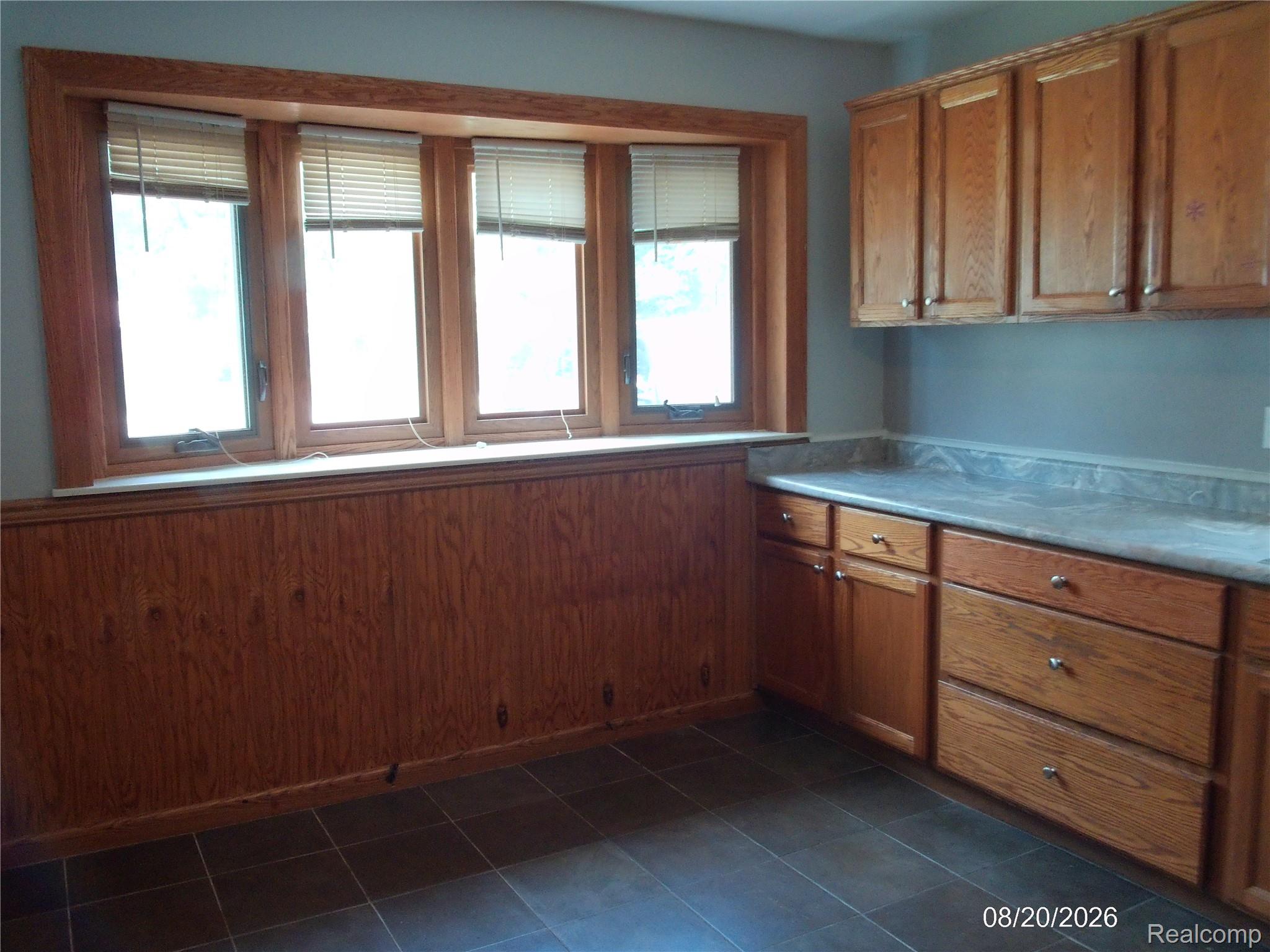 26445 Colgate Street Inkster, MI 48141 - Photo 10 of 35 Bay window with wood trim, wood paneling, wood-finish cabinetry, and dark-toned flooring