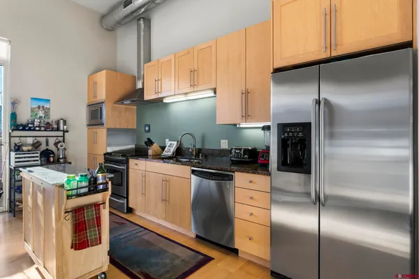 a kitchen with stainless steel appliances granite countertop a sink a stove and a refrigerator