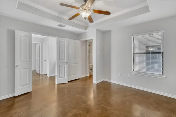 an empty room with wooden floor fan and windows