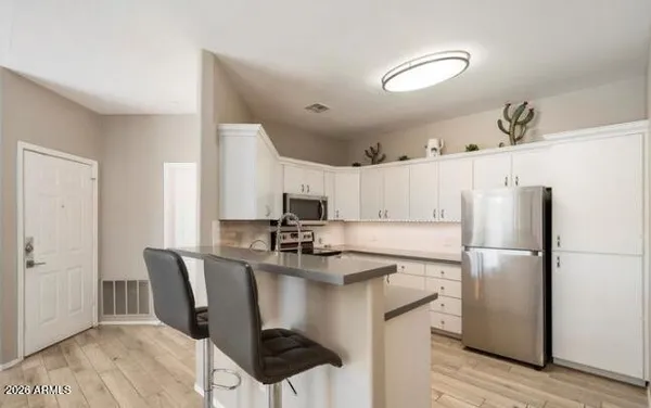 a kitchen with a refrigerator a stove a sink and a dining table with wooden floor