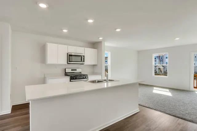 a kitchen with stainless steel appliances a sink a stove a microwave a sink a refrigerator and cabinets