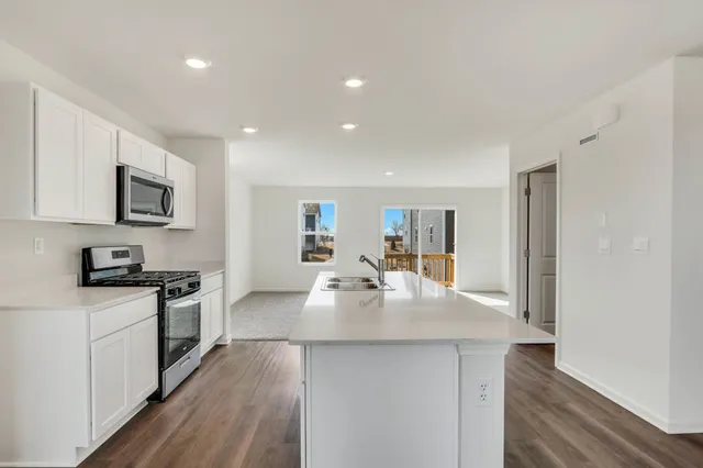 a large kitchen with kitchen island a stove a sink a refrigerator and cabinets