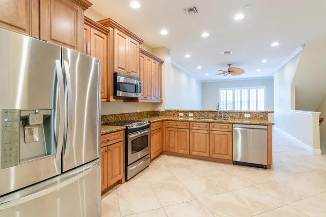 a kitchen with stainless steel appliances granite countertop a refrigerator a sink and a stove