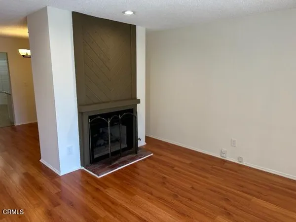 a view of an empty room with wooden floor and a fireplace