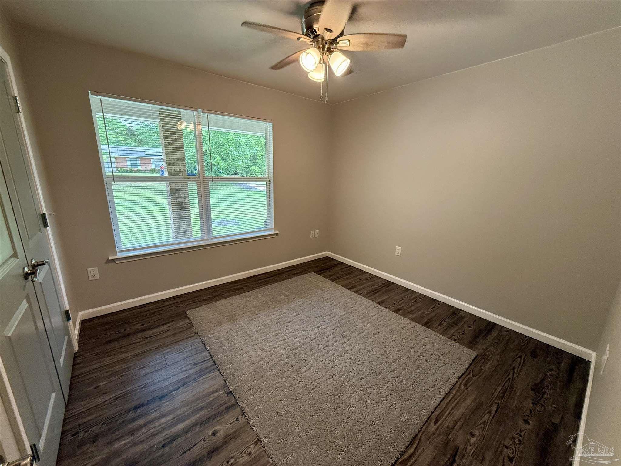 5553 Riviera Drive Milton, FL 32583 - Photo 11 of 23 an empty room with wooden floor fan and windows
