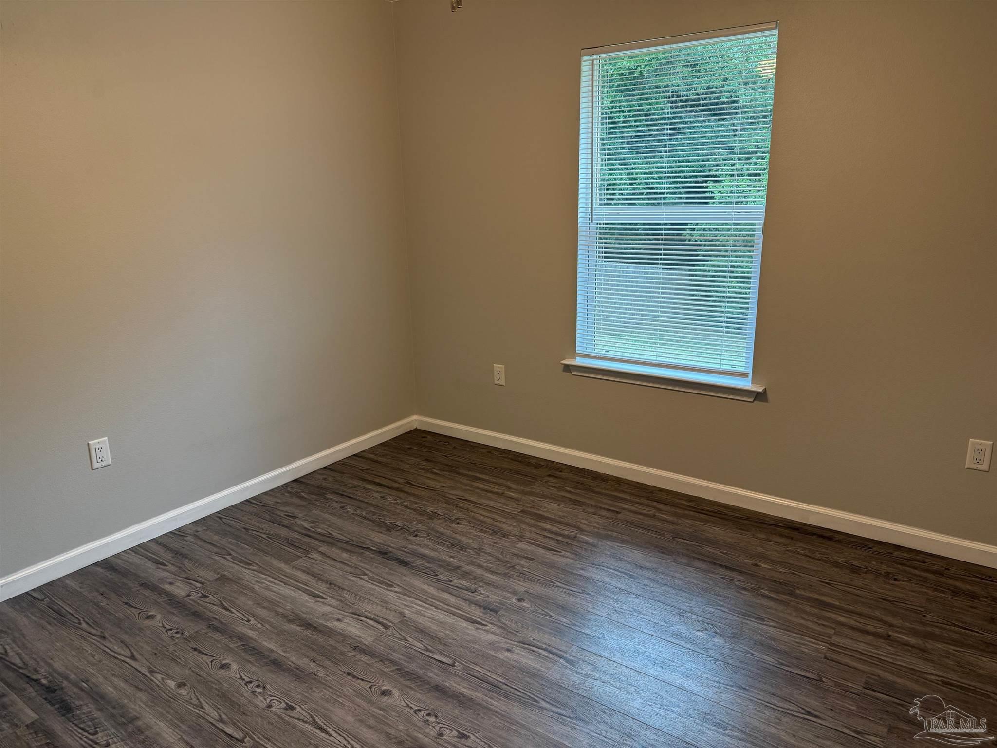 5553 Riviera Drive Milton, FL 32583 - Photo 12 of 23 a view of an empty room with wooden floor and a window