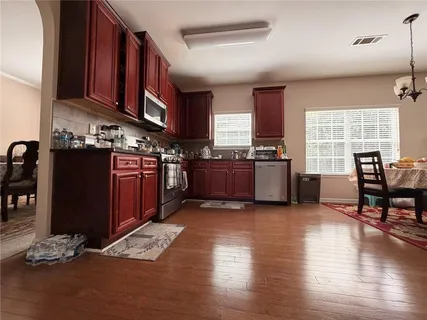 a kitchen with stainless steel appliances granite countertop a stove top oven a sink dishwasher and wooden cabinets with wooden floor